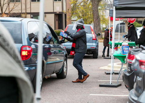 man handing resources to person in a car during a drive-through event