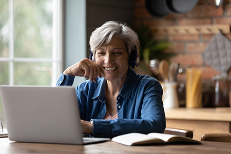 senior woman wearing headphones watching a laptop computer