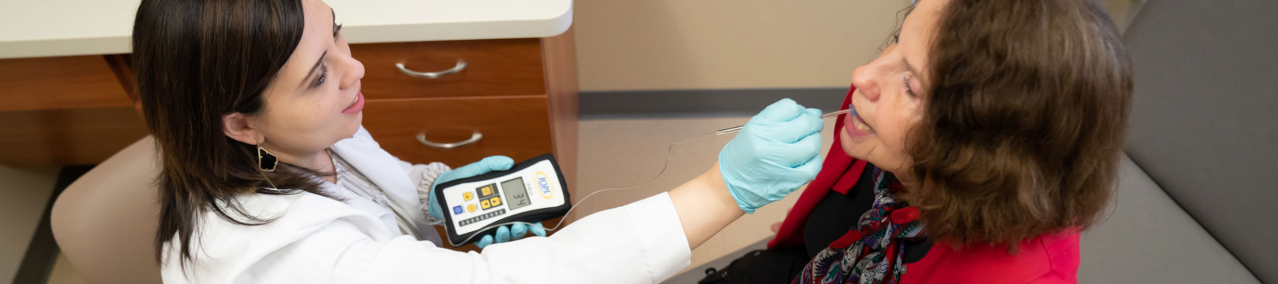 a female doctor inserts a research device into a research participant's mouth