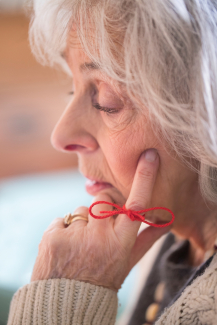 elderly woman with red string around her finger