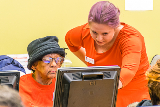 young person helping an elder at a computer
