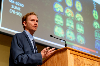 sterling johnson at podium in front of slide presentation of brain scans