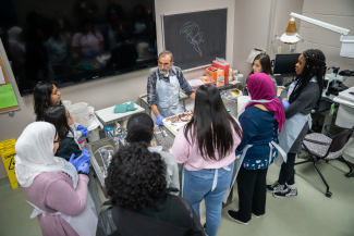 group of high school-aged women observing brain autopsy led by male pathologist