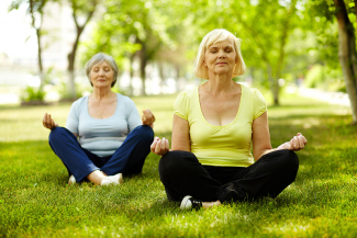 two senior women meditating in nature