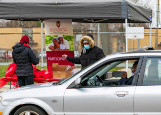 woman talking to person in a car at a drive-through resource fair