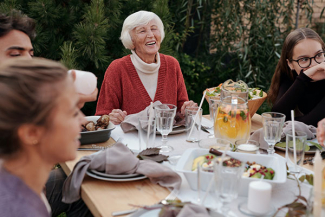 elderly woman at dinner table eating with others