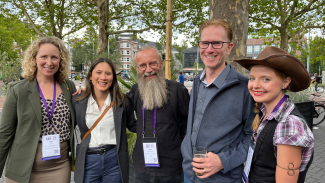 Drs. Amy Kind, Rachael Wilson, Henrik Zetterberg, Sterling Johnson, and Natascha Merten stand together for a photo outside in Amsterdam