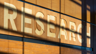 A photo of the entrance to the Health Sciences Learning Center (HSLC) at UW Hospital. On the wood paneled wall it says, "Research".