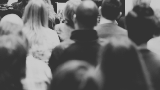 Black and white image of a group of people watching a presentation