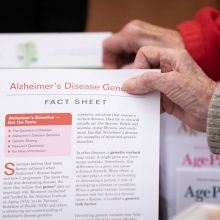 elderly hand picking up fact sheet about alzheimer's disease