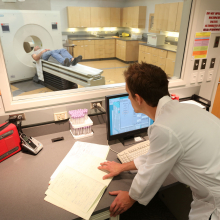 PET scan tech looking at man in PET machine