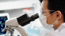 Stock photo of a man looking through a microscopt