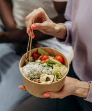 Stock photo of a salad and someone holding the bowl with pink nail polish on their hands