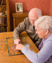 Stock photo of an older couple working on a puzzle at a table