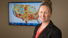 Photo of Dr. Amy Kind in front of a screen with a population map presented on it