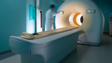 Stock photo of a medical technician working the controls of a PET scan machine