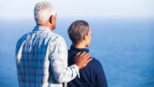 Photo of a couple overlooking water with their backs to the camera