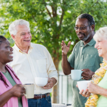 A group of older adults having a conversation outside and smiling