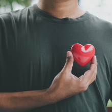 A person holding a shiny heart in front of their chest