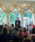 Former Wisconsin Governor Marty Schreiber talking at a podium in front of a crowd at the Governor's residence